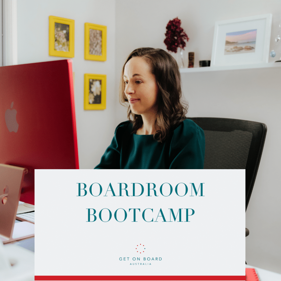 A lady in a green dress is sitting at her computer enjoying working through the Boardroom Bootcamp course.